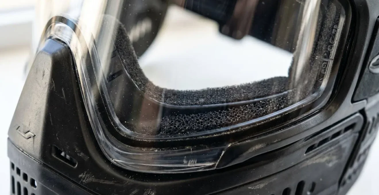 Gros plan macro sur un masque de paintball moderne montrant le verre en polycarbonate avec reflets lumineux et le joint en mousse étanche